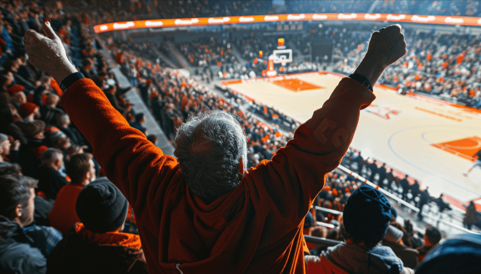 A man cheering on his basketball team at his seats on the court